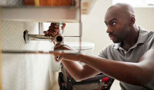 a male plumber fixing a bathroom faucet in Plano, TX - Plano, TX
